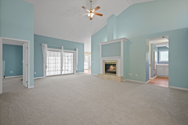 unfurnished living room with high vaulted ceiling, carpet floors, ceiling fan, baseboards, and a tile fireplace