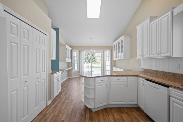 kitchen with dishwasher, vaulted ceiling, white cabinets, a peninsula, and wood finished floors