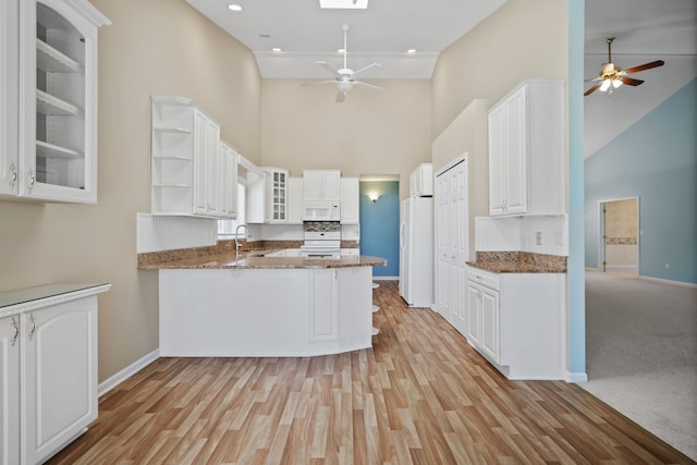 kitchen with a ceiling fan, high vaulted ceiling, white appliances, a peninsula, and a sink