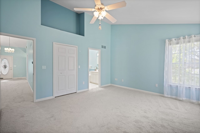 unfurnished bedroom with carpet floors, a chandelier, high vaulted ceiling, baseboards, and ensuite bath