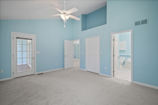 unfurnished bedroom with high vaulted ceiling, carpet, baseboards, ensuite bath, and a ceiling fan