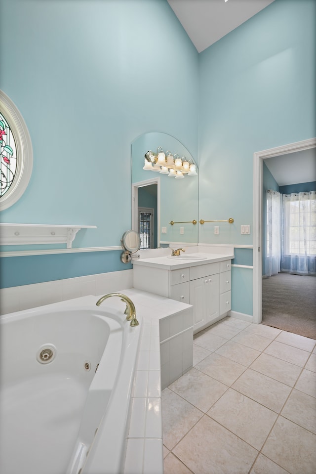 bathroom featuring a high ceiling, tile patterned flooring, a tub with jets, and vanity