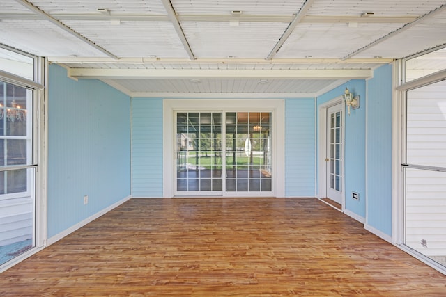 spare room with wood finished floors, beamed ceiling, and baseboards