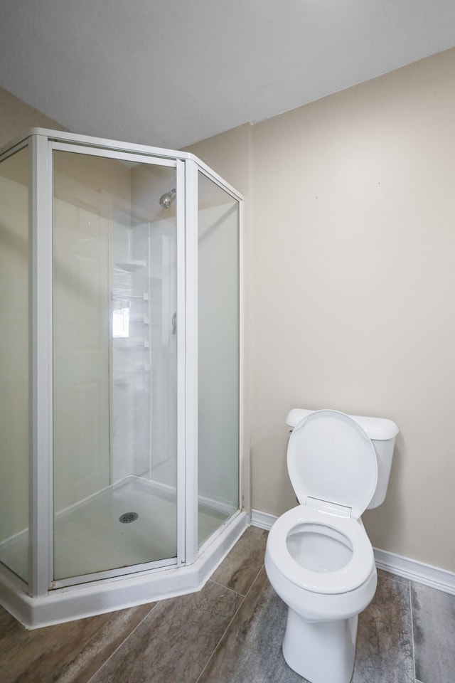 bathroom with baseboards, a shower stall, and toilet