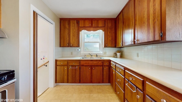 1200 Mohawk Ln, Saint Joseph, MI 49085 - kitchen featuring a sink, stainless steel electric range oven, decorative backsplash, brown cabinets, and light countertops