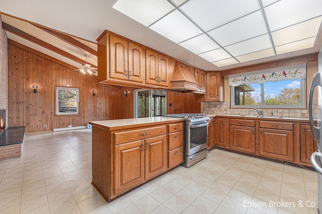 1657 W Kentview Dr NE, Grand Rapids, MI 49505 - kitchen featuring stainless steel range with gas cooktop, brown cabinetry, custom exhaust hood, light floors, and wooden walls