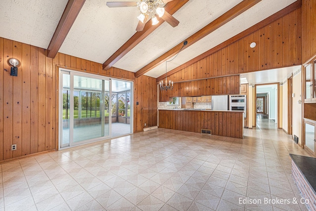1657 W Kentview Dr NE, Grand Rapids, MI 49505 - unfurnished living room with wood walls, beam ceiling, ceiling fan, high vaulted ceiling, and a chandelier