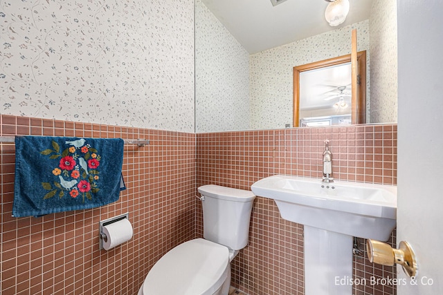 1657 W Kentview Dr NE, Grand Rapids, MI 49505 - bathroom featuring wallpapered walls, tile walls, a wainscoted wall, toilet, and lofted ceiling