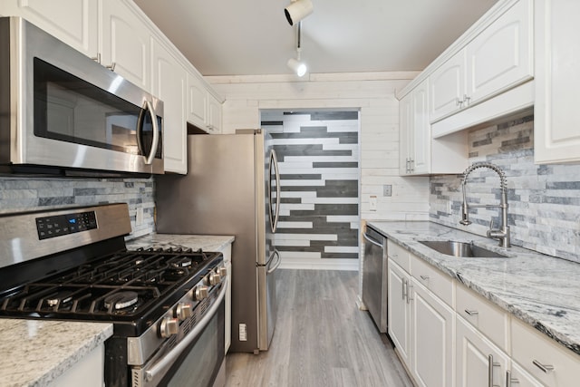 9601 Bayview Dr # 301, Ypsilanti, MI 48197 - kitchen featuring stainless steel appliances, a sink, white cabinets, and wooden walls