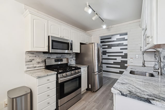 9601 Bayview Dr # 301, Ypsilanti, MI 48197 - kitchen with appliances with stainless steel finishes, a sink, white cabinets, backsplash, and wooden walls