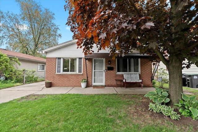 view of front of house with brick siding, a front lawn, and a patio area