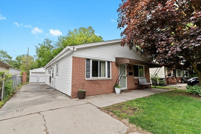 view of front of home featuring brick siding, a detached garage, and an outdoor structure