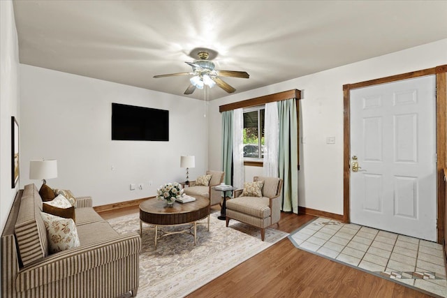 living area featuring light wood-type flooring, a ceiling fan, and baseboards