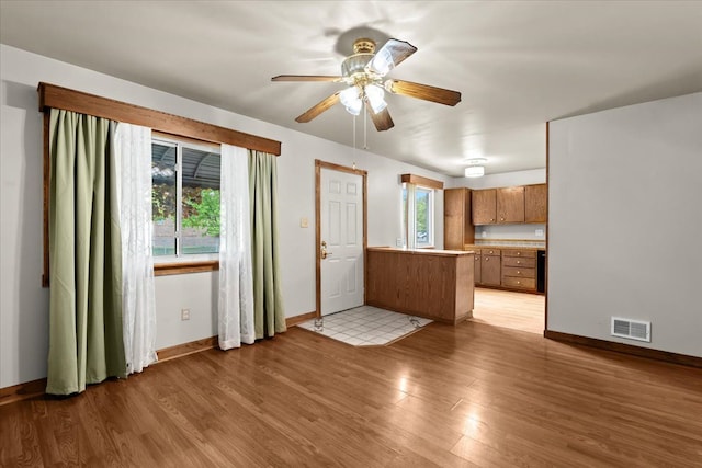 kitchen with a peninsula, brown cabinets, baseboards, and light wood-style flooring