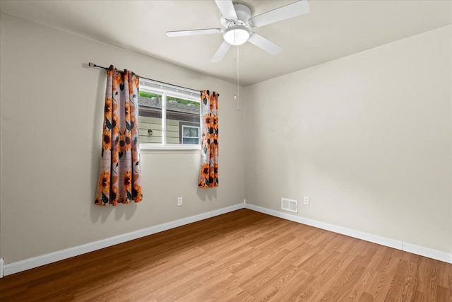 empty room with wood finished floors, baseboards, and a ceiling fan