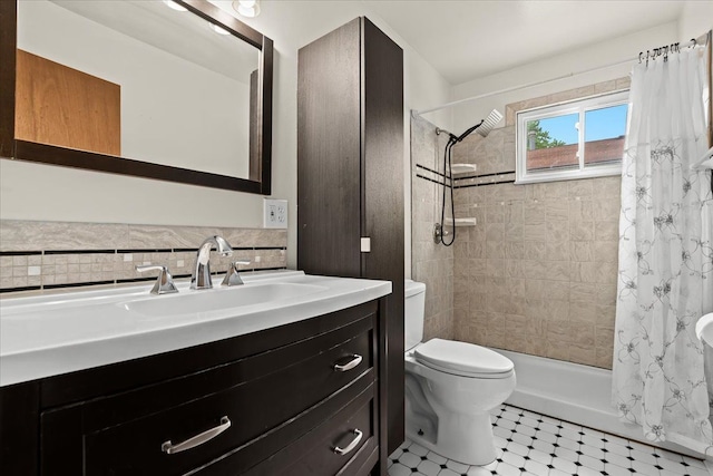 full bathroom featuring toilet, a tile shower, and vanity