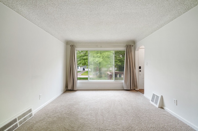 carpeted empty room with a textured ceiling and baseboards