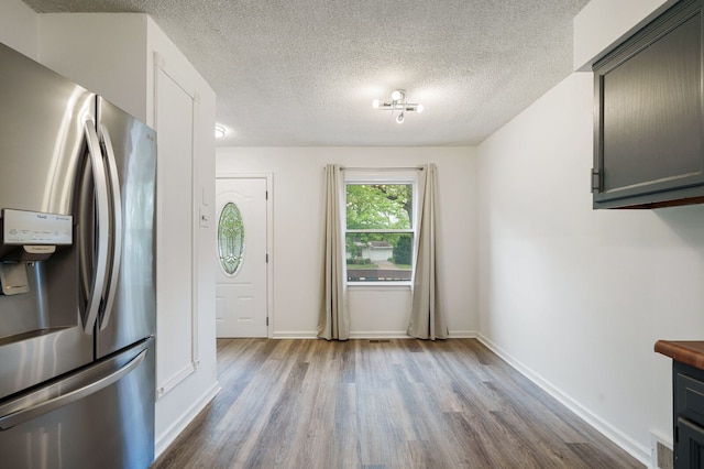 kitchen featuring stainless steel fridge with ice dispenser, wood finished floors, a textured ceiling, and baseboards