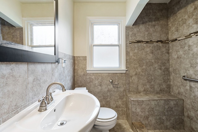 full bath with a sink, toilet, tile walls, and tiled shower