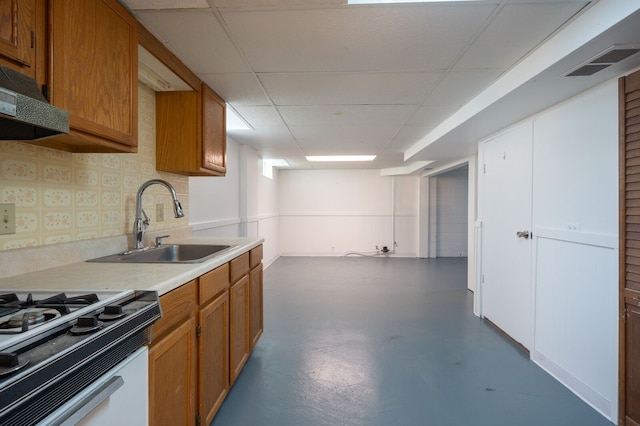 kitchen featuring a sink, concrete flooring, brown cabinets, light countertops, and gas range