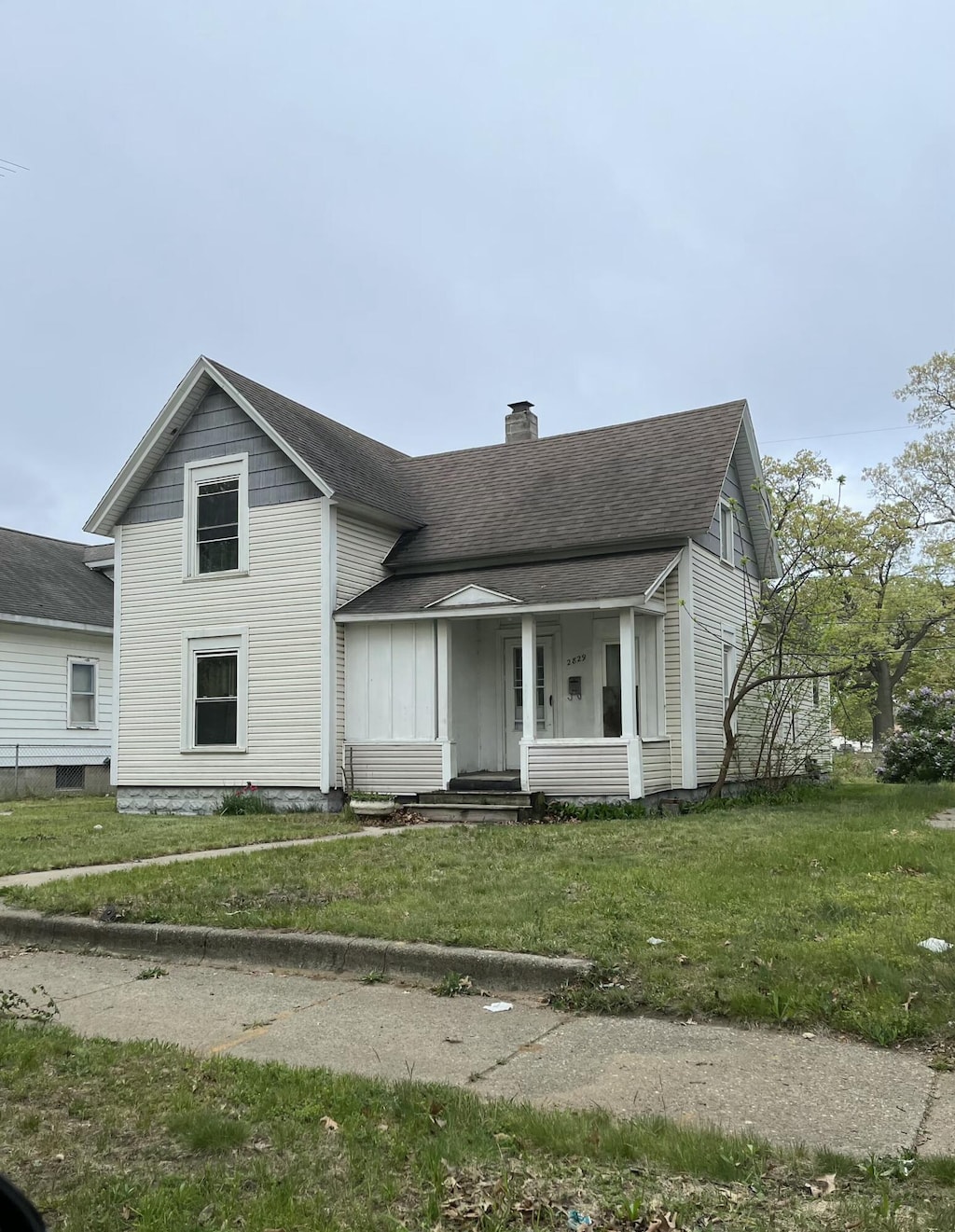 2829 Leahy St, Muskegon, MI 49444 - traditional home featuring a chimney, roof with shingles, a front lawn, and covered porch