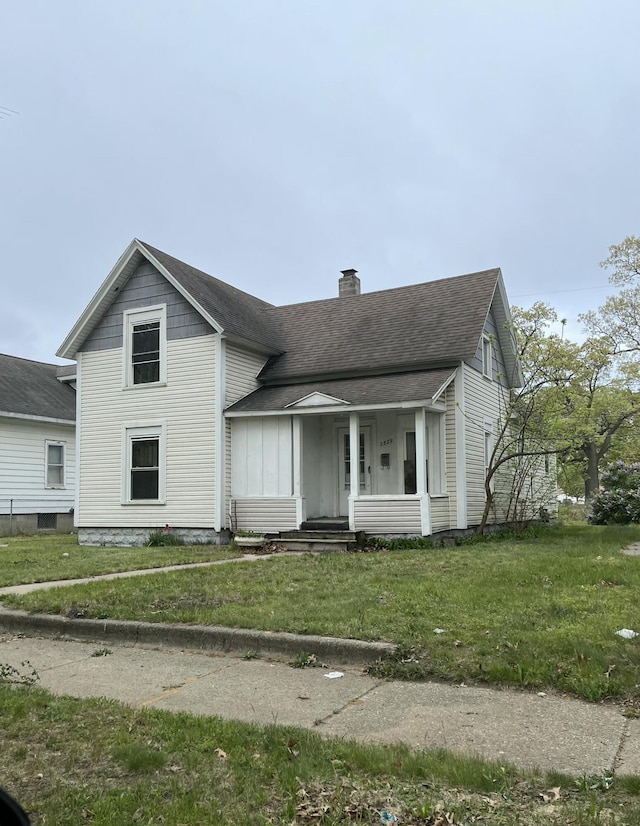 2829 Leahy St, Muskegon, MI 49444 - traditional home featuring a chimney, roof with shingles, a front lawn, and covered porch