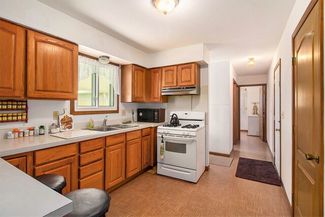 3480 S Vassar Rd, Burton, MI 48519 - kitchen featuring white gas stove, a sink, black microwave, under cabinet range hood, and brown cabinetry