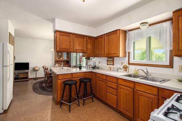 3480 S Vassar Rd, Burton, MI 48519 - kitchen featuring a sink, light countertops, brown cabinetry, and white appliances