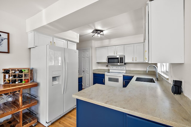 2015 Hazel Ave, Wixom, MI 48393 - kitchen featuring white appliances, a sink, white cabinets, blue cabinetry, and a peninsula