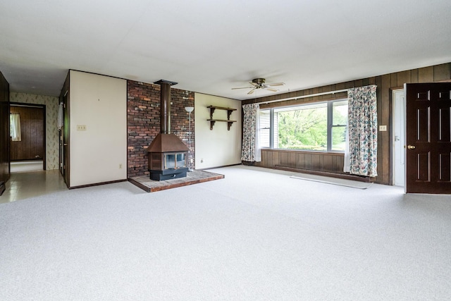 5575 Meadowbrook Rd, Eau Claire, MI 49111 - unfurnished living room with a ceiling fan, a wood stove, carpet floors, wood walls, and baseboards