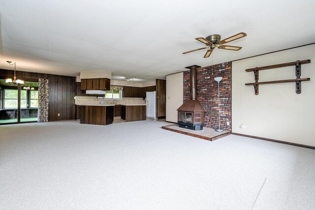 5575 Meadowbrook Rd, Eau Claire, MI 49111 - unfurnished living room featuring a wood stove, a chandelier, ceiling fan, light carpet, and baseboards