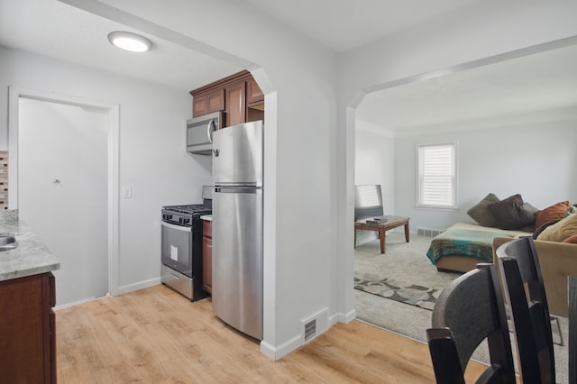 26613 W Hills Dr, Inkster, MI 48141 - kitchen featuring stainless steel appliances, light wood-style flooring, arched walkways, and open floor plan