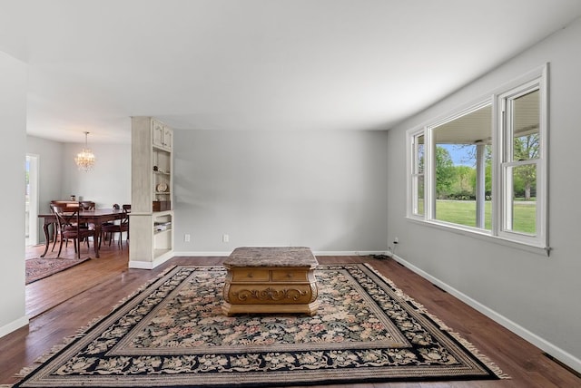 living area with a chandelier, dark wood finished floors, and baseboards