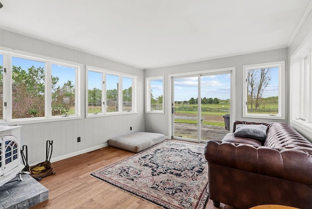 sunroom / solarium featuring wood finished floors, crown molding, and baseboards