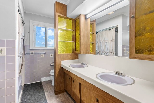 bathroom with crown molding, toilet, tile walls, double vanity, and wood finished floors