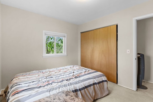 bedroom featuring light colored carpet, a closet, and baseboards