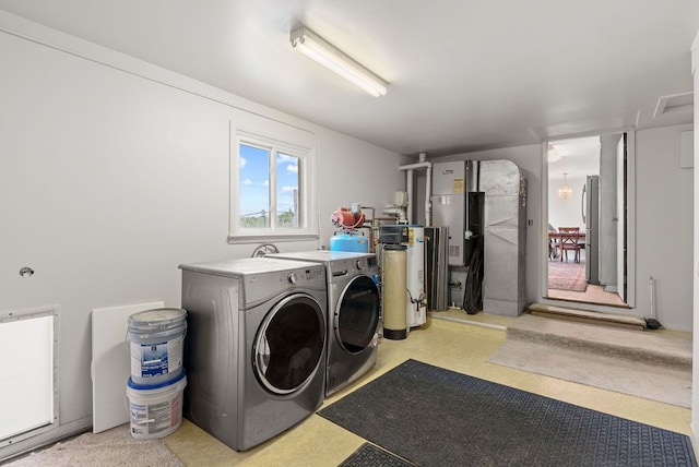 clothes washing area featuring washing machine and clothes dryer and water heater