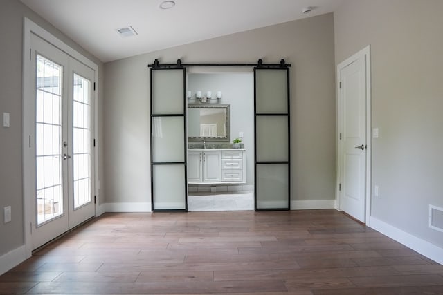 278 W Saint Clair St, Romeo, MI 48065 - unfurnished bedroom featuring a barn door, vaulted ceiling, light wood-style floors, and multiple windows