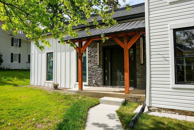 278 W Saint Clair St, Romeo, MI 48065 - view of exterior entry with a lawn, board and batten siding, roof with shingles, stone siding, and a porch