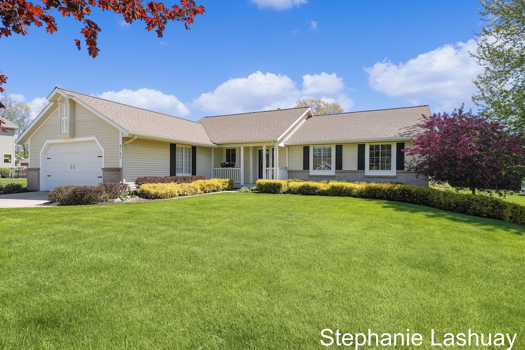 8740 Pleasant Meadows Dr NE, Rockford, MI 49341 - ranch-style house featuring a front yard, a garage, brick siding, concrete driveway, and roof with shingles