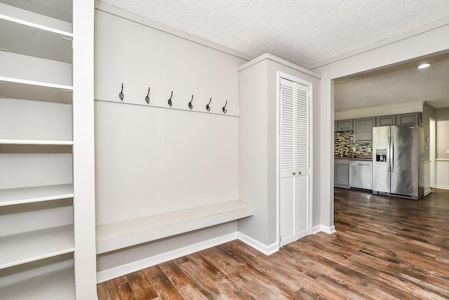 mudroom with dark wood-type flooring, a textured ceiling, and baseboards