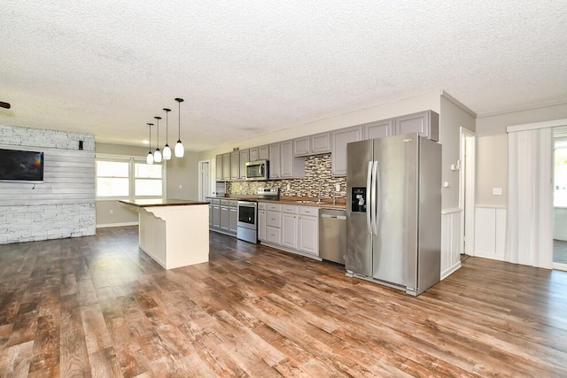 kitchen with stainless steel appliances, a textured ceiling, gray cabinetry, dark wood finished floors, and dark countertops