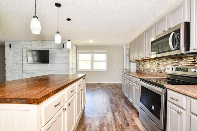 kitchen with stainless steel appliances, wood counters, a textured ceiling, dark wood-type flooring, and baseboards