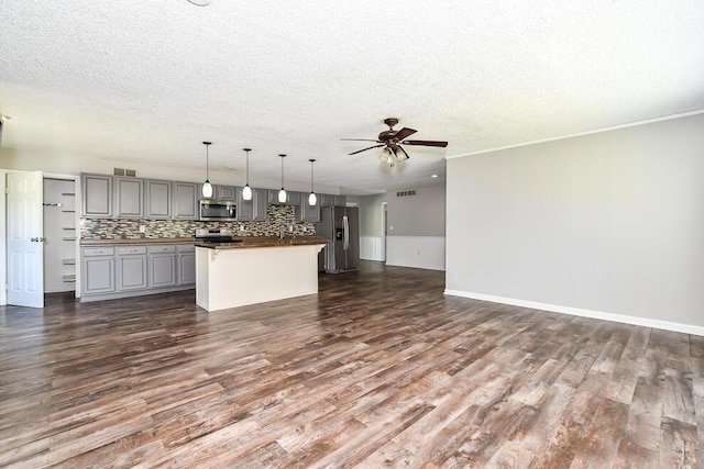 kitchen with stainless steel appliances, a ceiling fan, a textured ceiling, open floor plan, and dark wood finished floors