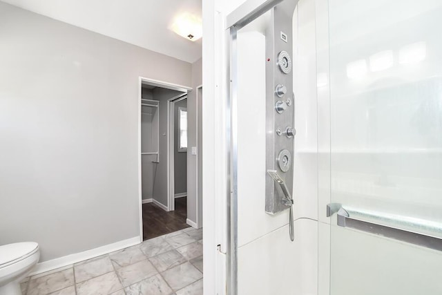 full bath with a stall shower, baseboards, and toilet