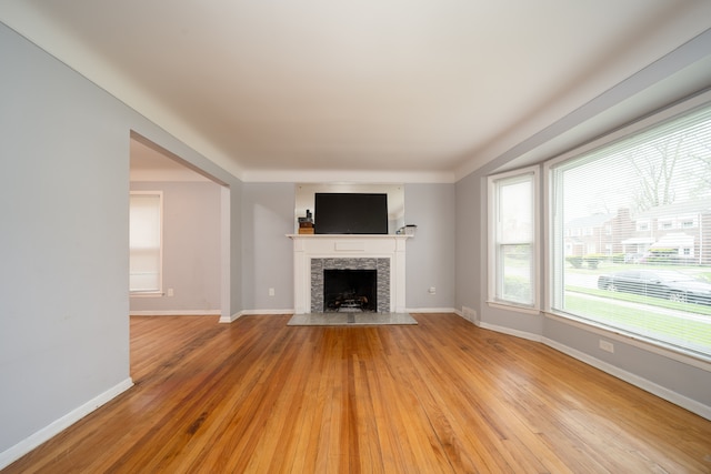unfurnished living room featuring light wood-style floors, a fireplace, and baseboards