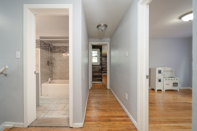 hall with light wood-style flooring and baseboards