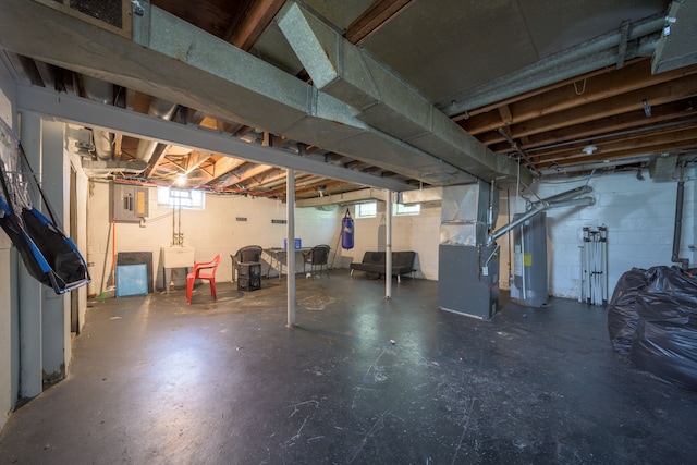 below grade area with heating unit, concrete block wall, gas water heater, and a sink