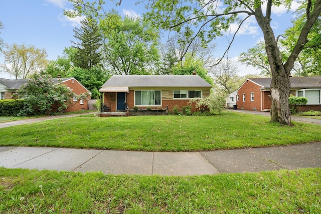 view of front facade with brick siding, a front lawn, and a chimney