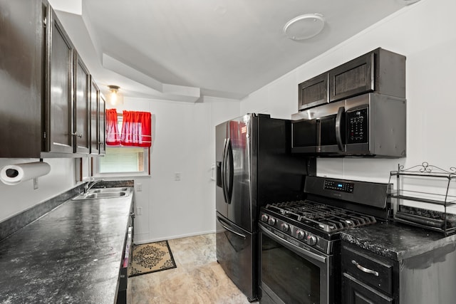 kitchen featuring appliances with stainless steel finishes, a sink, dark countertops, dark brown cabinets, and arched walkways